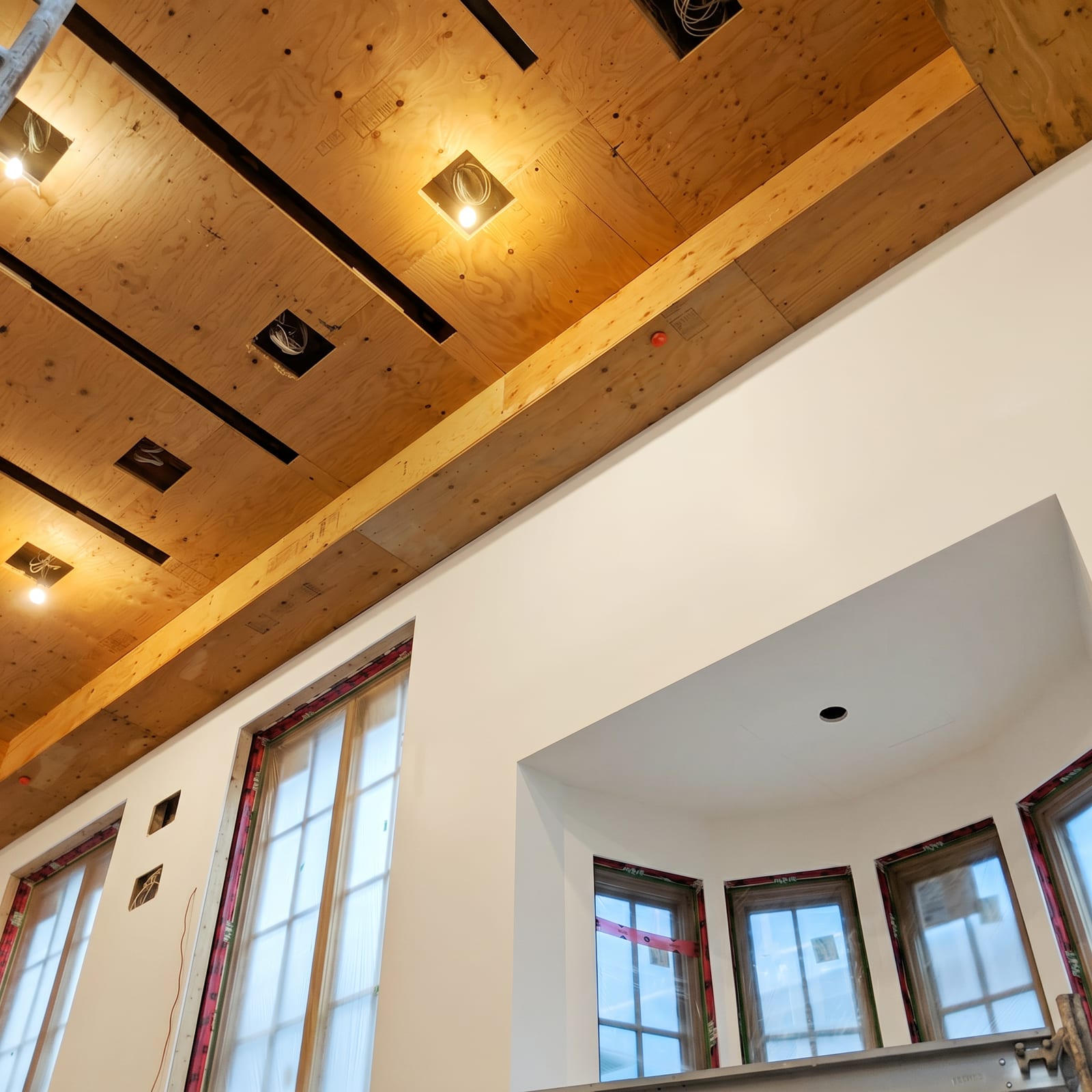 Exposed timber ceiling above finished walls and a bow window.