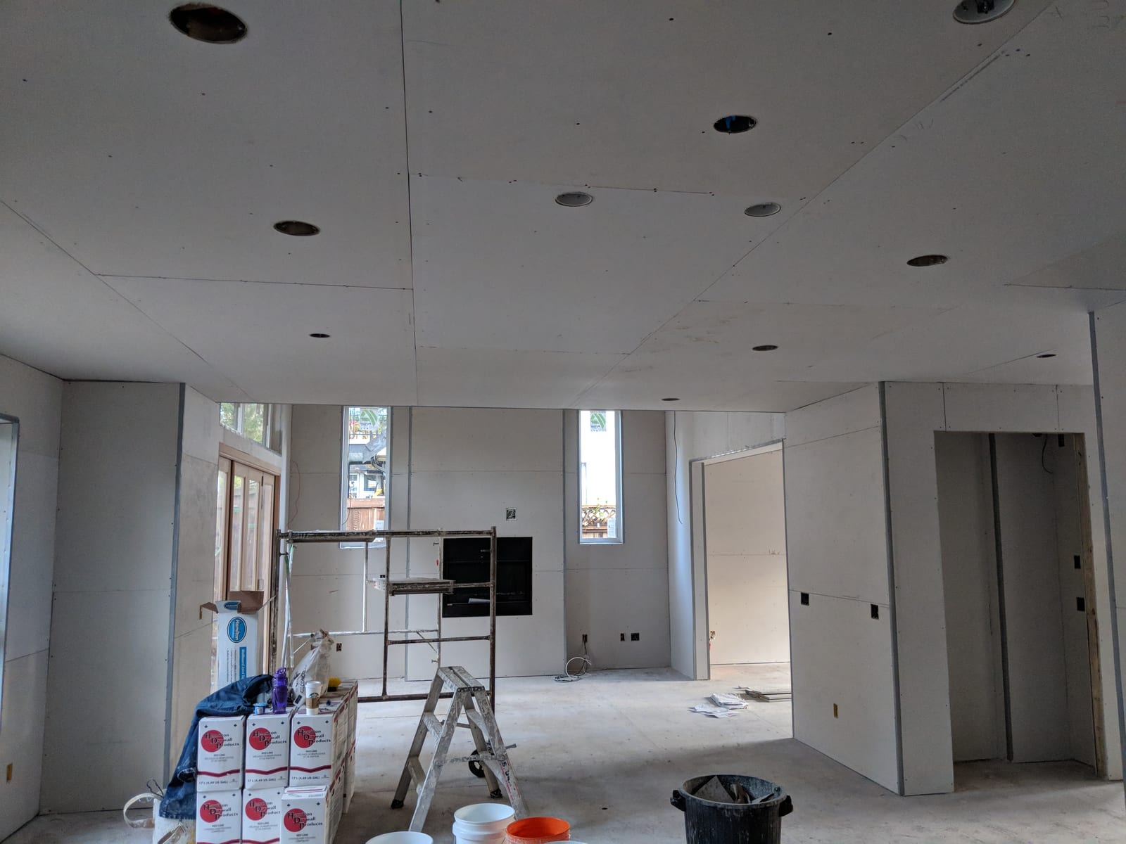 Large open-plan room with finished walls, concrete floor prepped for install.