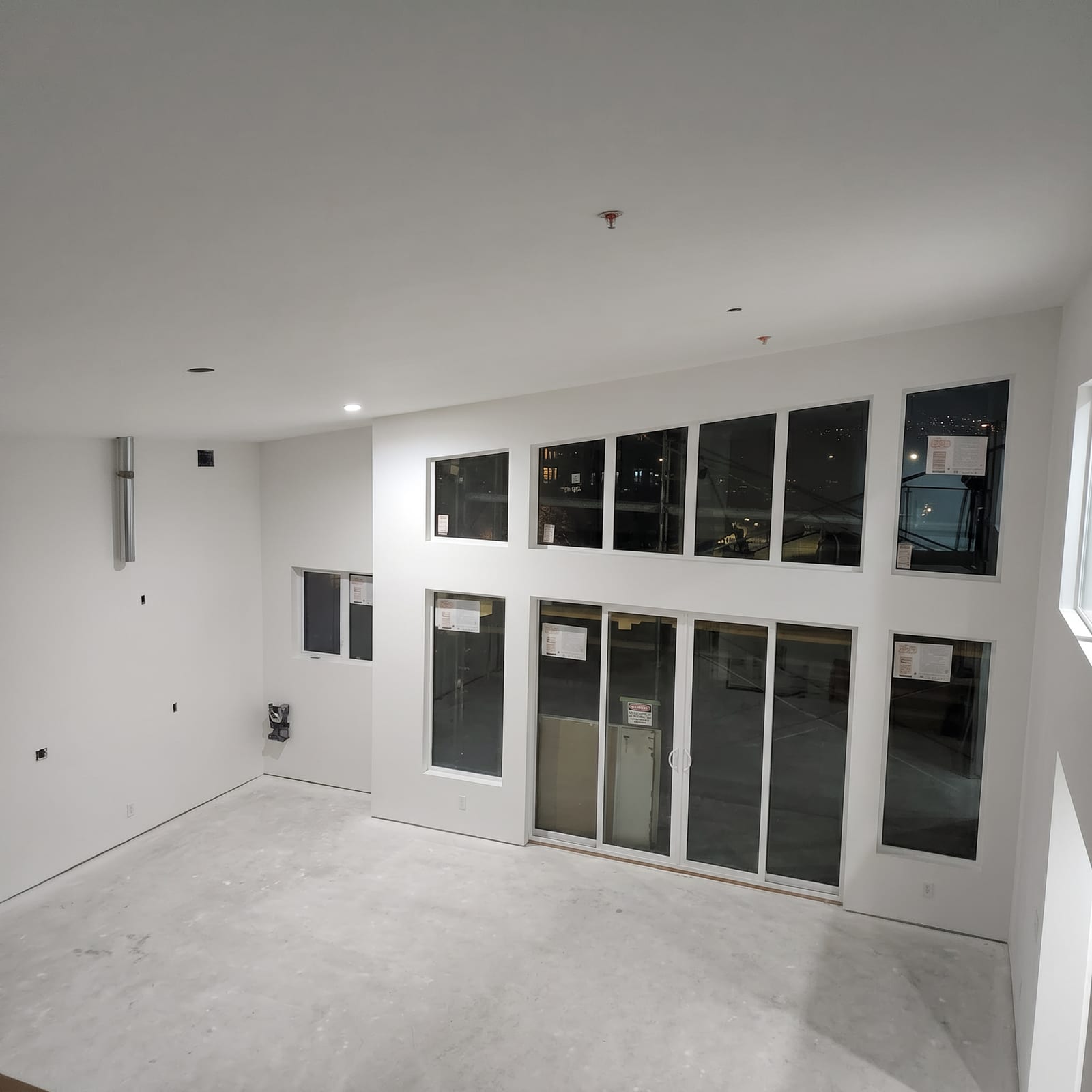 Finished room with a tall window wall and patio doors.