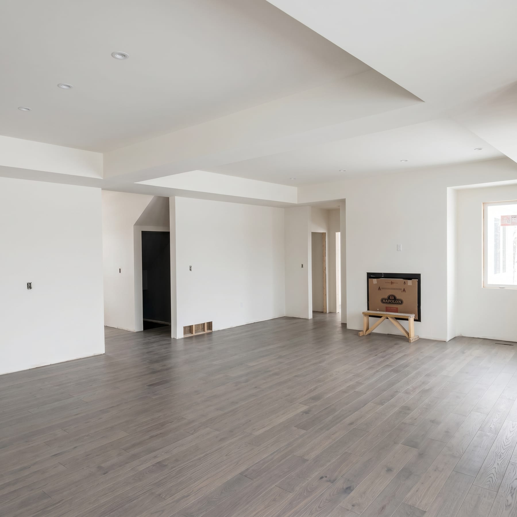Finished coffered-ceiling room with hardwood floor and clean white walls.