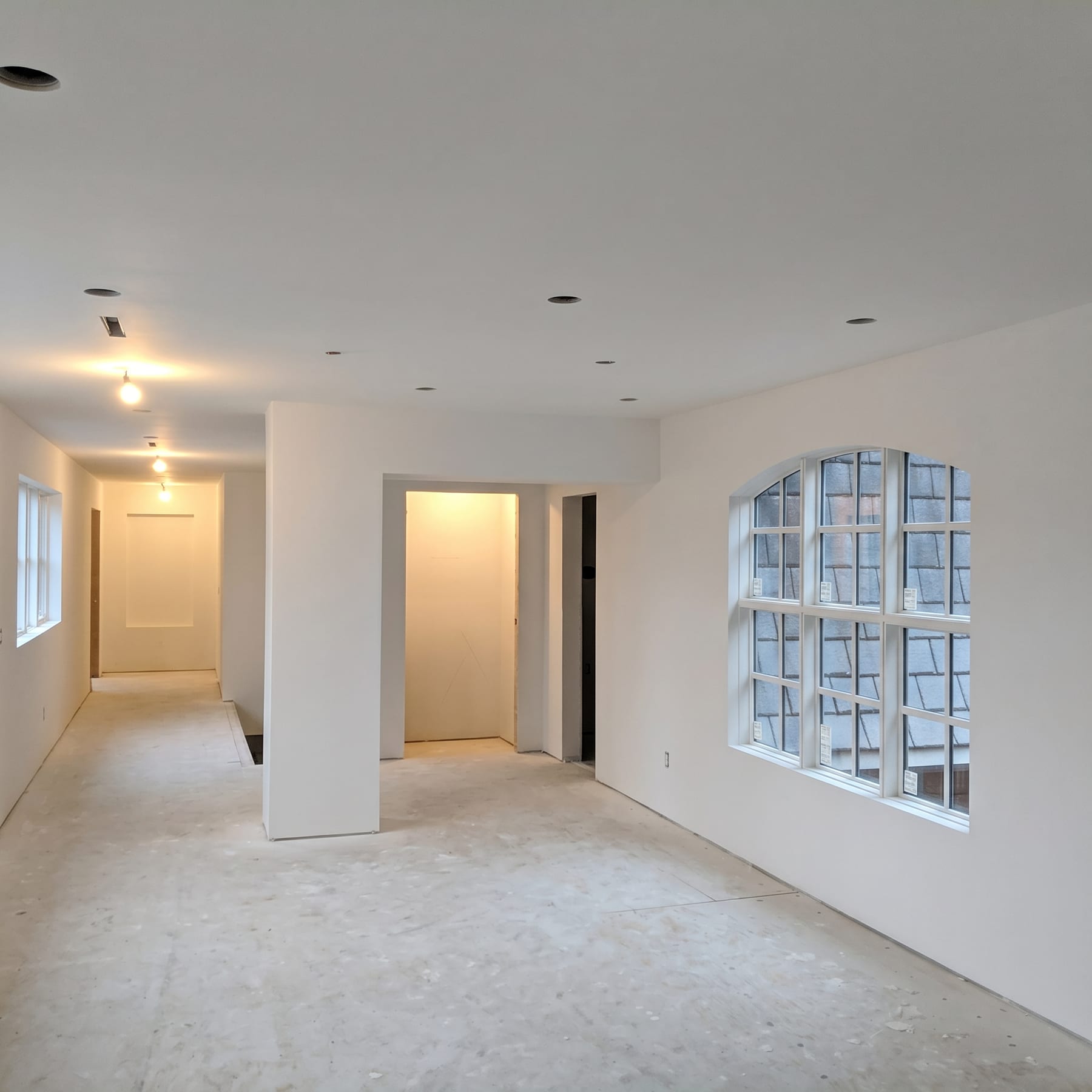 Finished hallway with arched window and recessed lighting.