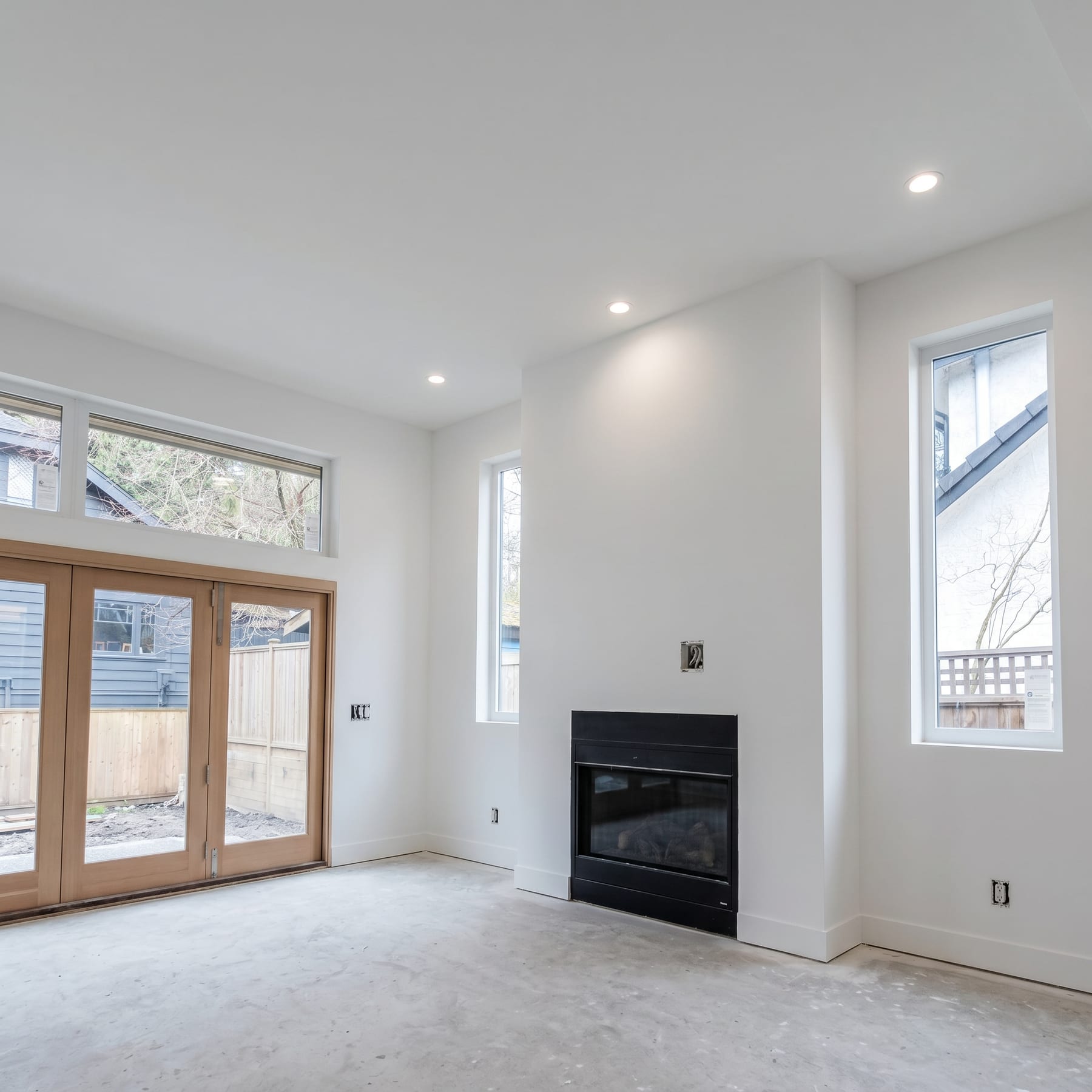 Finished living area with fireplace, floor-to-ceiling windows and patio doors.
